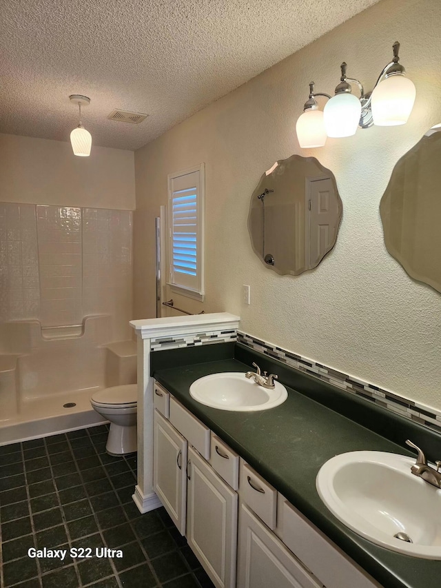 bathroom with walk in shower, tile patterned floors, toilet, a textured ceiling, and vanity