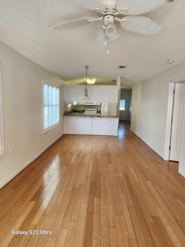 unfurnished living room with ceiling fan, a textured ceiling, and light wood-type flooring