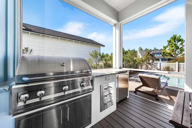 wooden deck featuring a fenced in pool, an outdoor kitchen, and grilling area