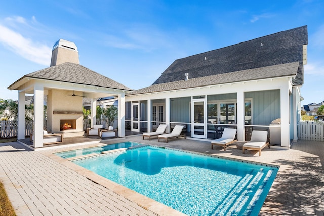 back of property featuring exterior fireplace, a patio area, a sunroom, and ceiling fan