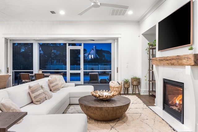 living room featuring ceiling fan, ornamental molding, a premium fireplace, and hardwood / wood-style floors