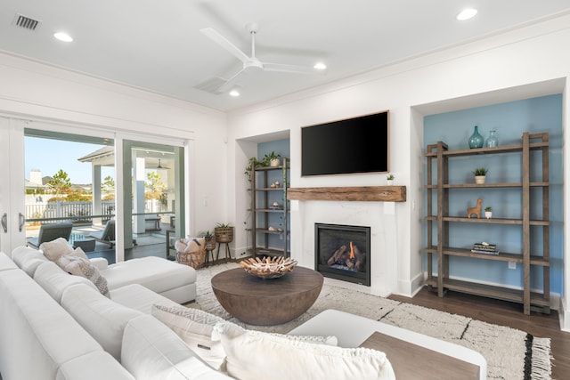 living room featuring crown molding, a premium fireplace, ceiling fan, and hardwood / wood-style flooring