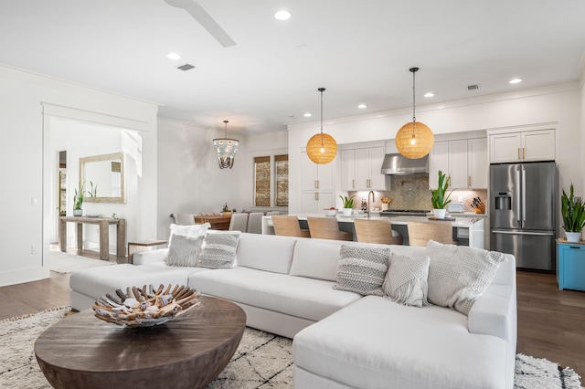 living room with crown molding, sink, and light hardwood / wood-style floors