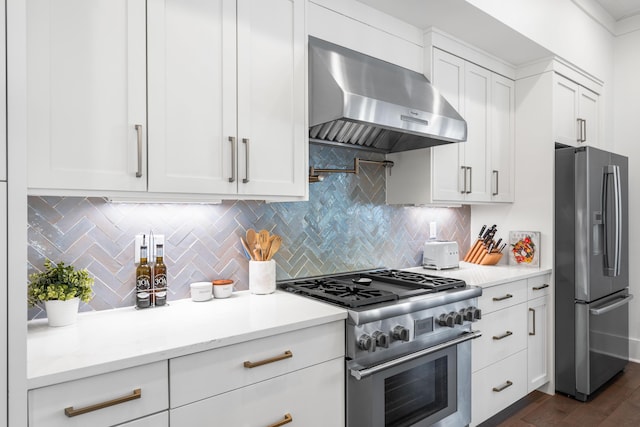 kitchen with wall chimney range hood, white cabinetry, stainless steel appliances, tasteful backsplash, and light stone countertops