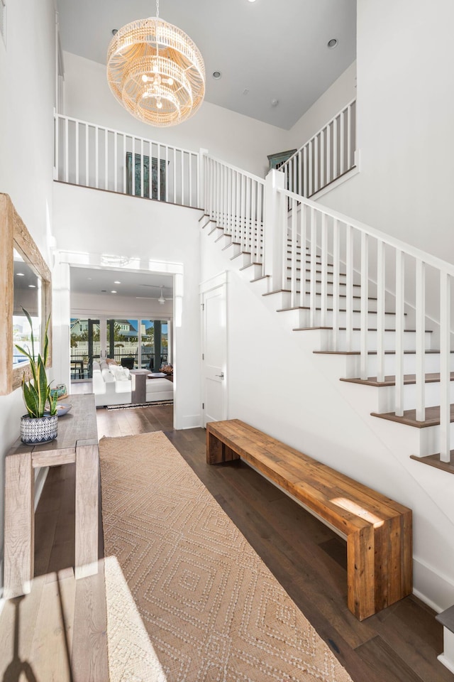 stairway featuring a towering ceiling, a chandelier, and hardwood / wood-style floors