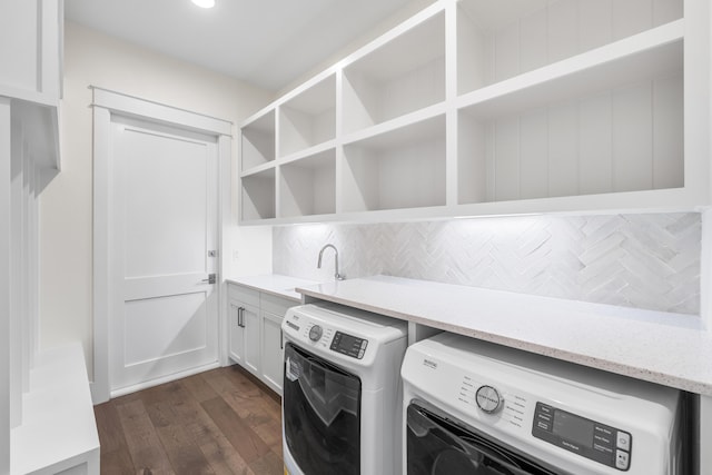 laundry room featuring dark wood-type flooring, cabinets, washer and clothes dryer, and sink