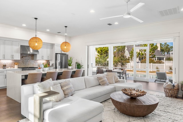 living room with hardwood / wood-style floors, crown molding, plenty of natural light, and ceiling fan