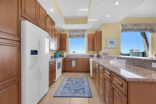 kitchen with white appliances, recessed lighting, a peninsula, and a tray ceiling