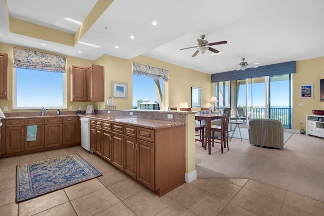 kitchen featuring plenty of natural light, a peninsula, light stone countertops, and a sink