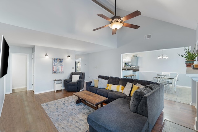 living room with hardwood / wood-style floors, ceiling fan with notable chandelier, and high vaulted ceiling