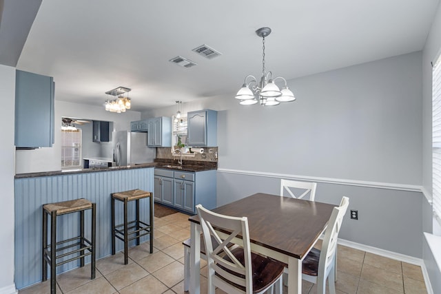 tiled dining room with ceiling fan with notable chandelier and sink