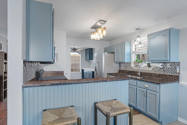 kitchen featuring kitchen peninsula, stainless steel appliances, blue cabinets, and sink