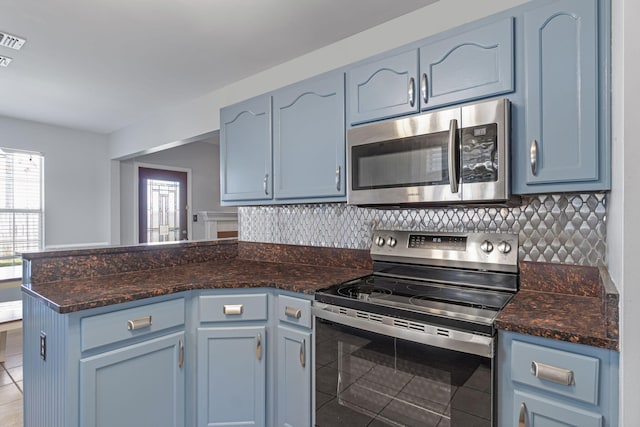 kitchen featuring blue cabinets, kitchen peninsula, appliances with stainless steel finishes, and tasteful backsplash