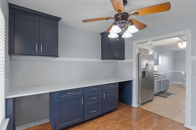 kitchen featuring ceiling fan, stainless steel fridge, light hardwood / wood-style floors, and blue cabinets