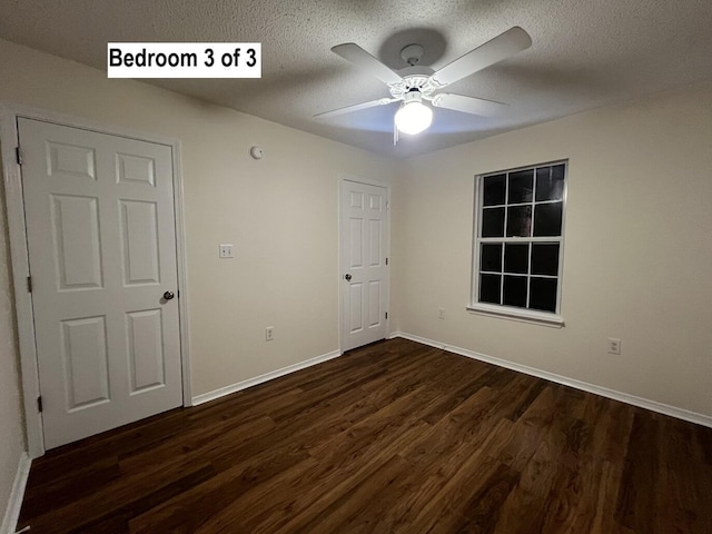 unfurnished bedroom with a textured ceiling, ceiling fan, and dark wood-type flooring