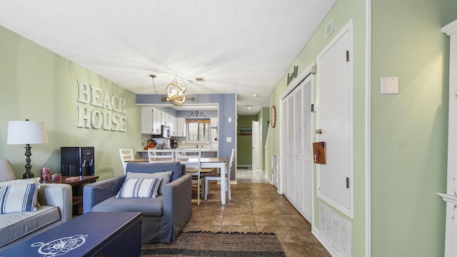 tiled living room featuring a textured ceiling, an inviting chandelier, and sink