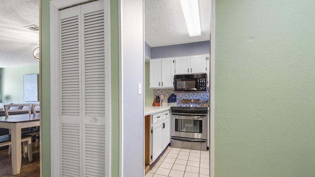 kitchen with stainless steel electric stove, tasteful backsplash, white cabinets, and a textured ceiling