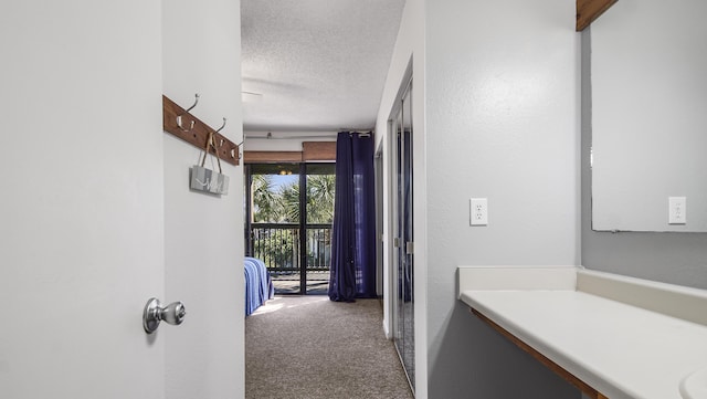 hall featuring carpet floors and a textured ceiling