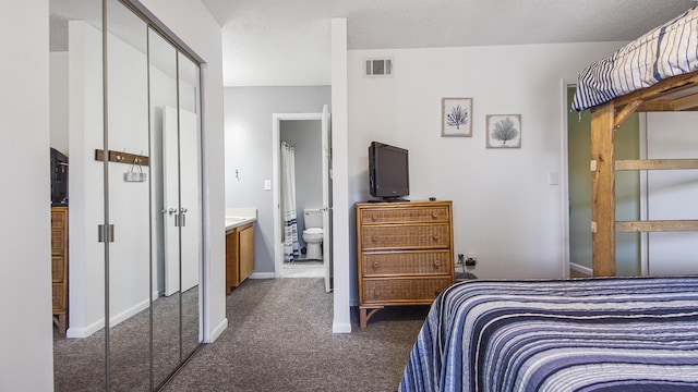 carpeted bedroom featuring connected bathroom and a textured ceiling