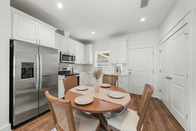 kitchen with white cabinets, appliances with stainless steel finishes, and dark hardwood / wood-style floors