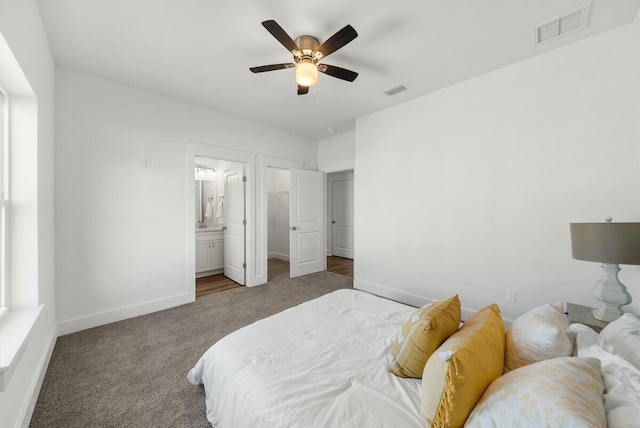 carpeted bedroom with ensuite bathroom and ceiling fan