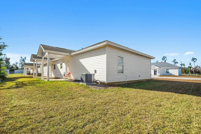 rear view of property featuring a yard and central AC