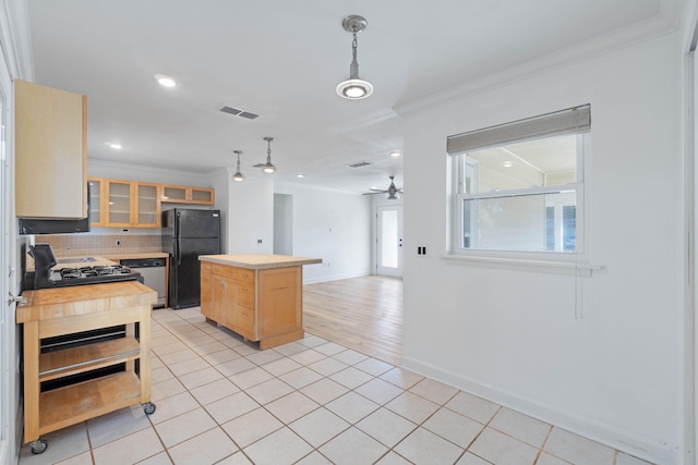 kitchen featuring black refrigerator, light brown cabinetry, decorative backsplash, a center island, and hanging light fixtures