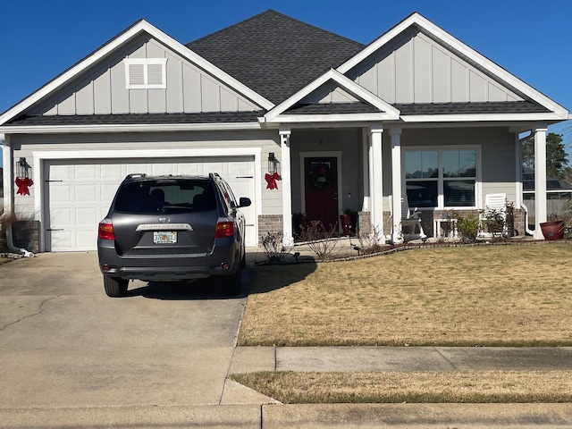 view of front of home featuring a porch, a garage, and a front lawn