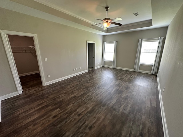 238 Partridge Ln, Freeport, FL 32439 - unfurnished bedroom with a tray ceiling, dark wood finished floors, a walk in closet, and a ceiling fan
