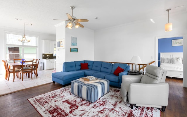 living room with hardwood / wood-style flooring, ornamental molding, and ceiling fan with notable chandelier