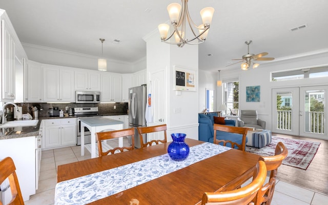 dining space with light tile patterned flooring, sink, crown molding, and french doors