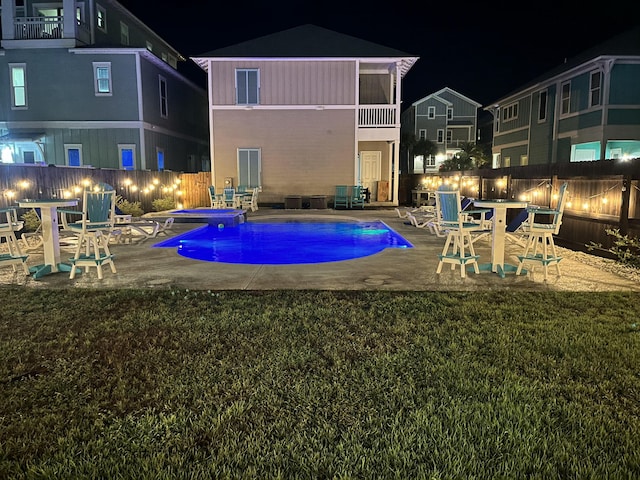 pool at twilight featuring a lawn and a patio