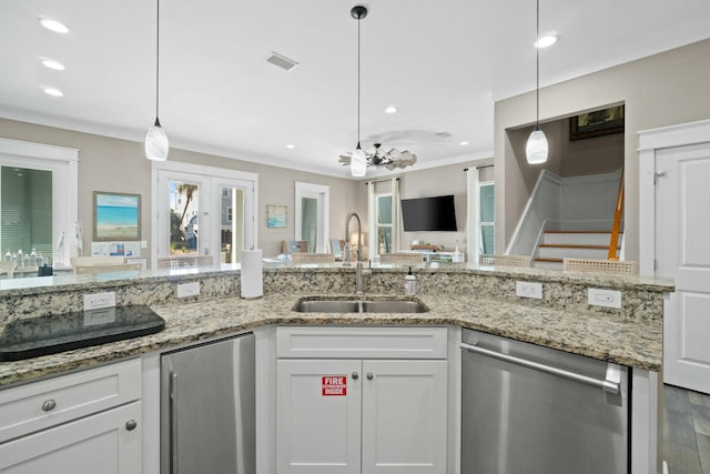 kitchen with hardwood / wood-style floors, white cabinets, hanging light fixtures, sink, and appliances with stainless steel finishes