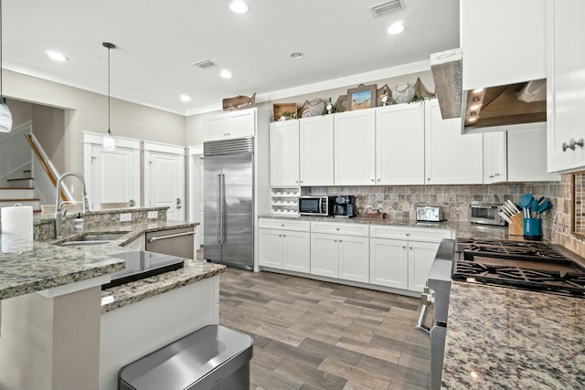 kitchen featuring sink, appliances with stainless steel finishes, decorative light fixtures, light hardwood / wood-style floors, and white cabinetry