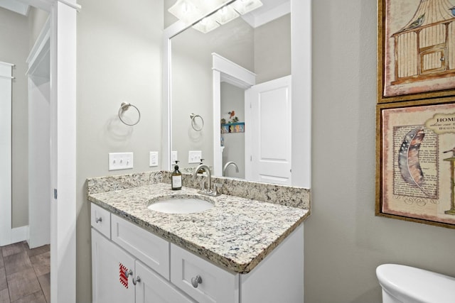 bathroom with wood-type flooring, vanity, and toilet