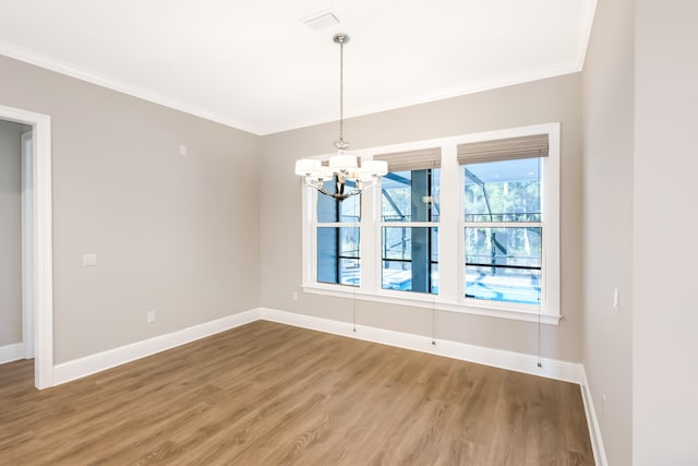 spare room featuring hardwood / wood-style floors, crown molding, and a notable chandelier