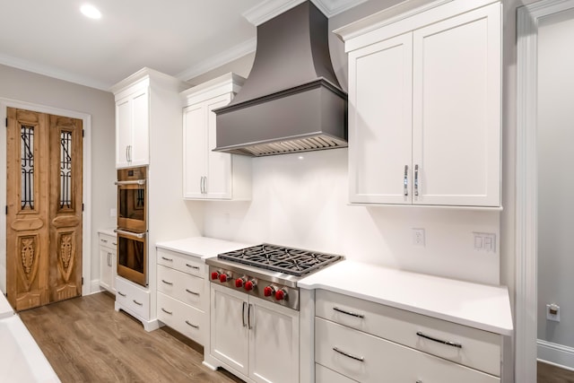 kitchen with white cabinets, custom range hood, stainless steel appliances, and ornamental molding