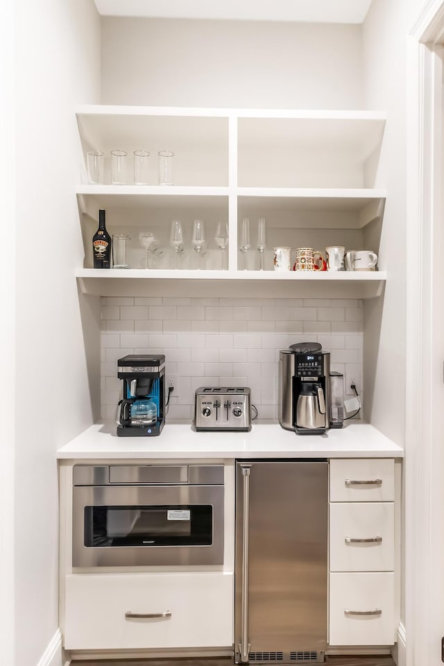 bar featuring appliances with stainless steel finishes and tasteful backsplash