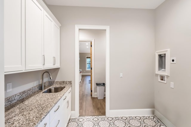 laundry room with hookup for an electric dryer, light tile patterned flooring, cabinets, and sink