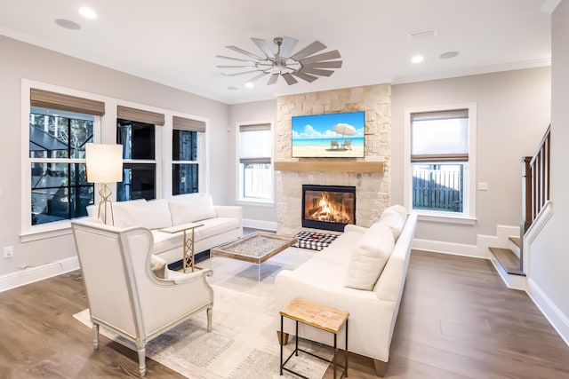 living room with ceiling fan, wood-type flooring, a fireplace, and ornamental molding