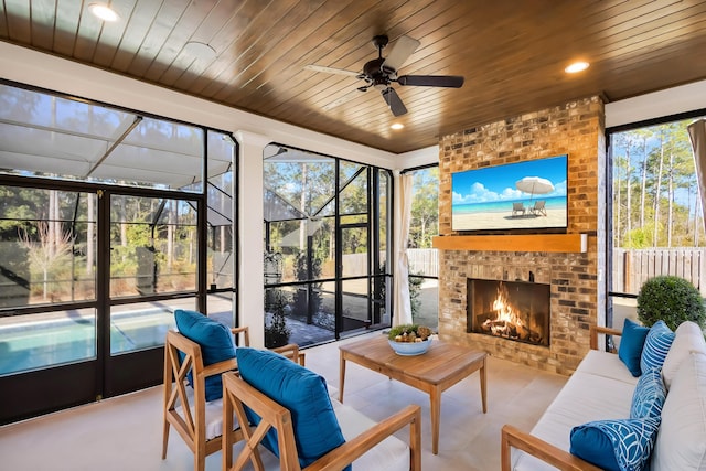 sunroom / solarium with a brick fireplace, ceiling fan, and wooden ceiling