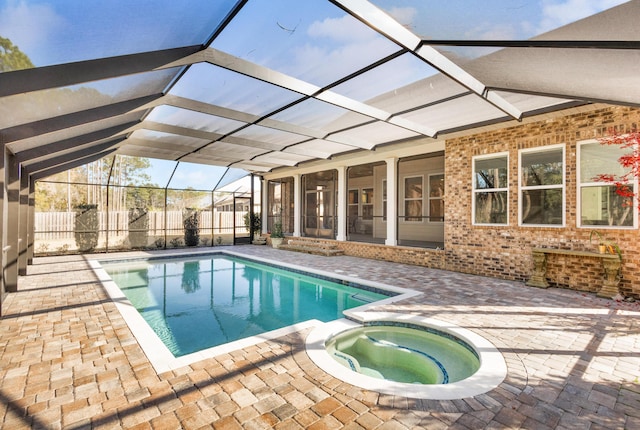 view of swimming pool featuring glass enclosure, an in ground hot tub, and a patio area