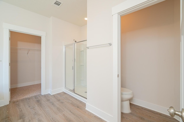 bathroom with toilet, an enclosed shower, and wood-type flooring