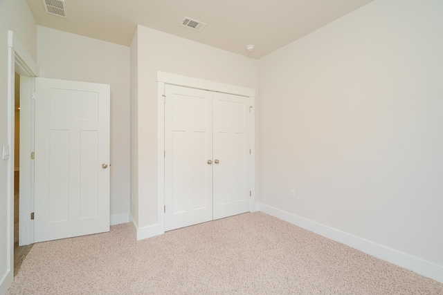 unfurnished bedroom with light carpet and a closet