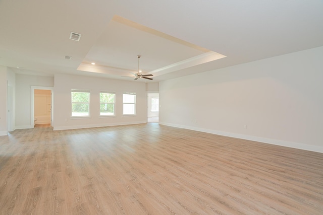 spare room with a raised ceiling, ceiling fan, and light hardwood / wood-style flooring