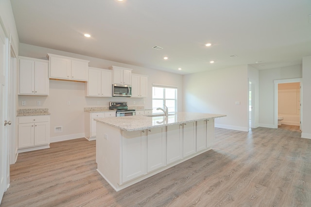 kitchen featuring sink, light hardwood / wood-style floors, a kitchen island with sink, white cabinets, and appliances with stainless steel finishes