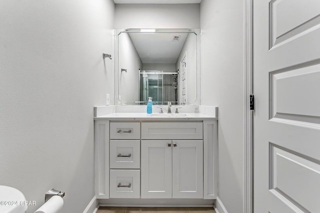 bathroom featuring a shower with door and vanity