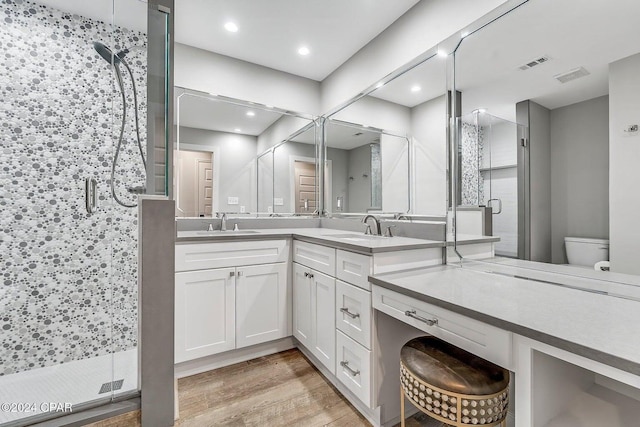 bathroom featuring hardwood / wood-style floors, vanity, toilet, and a shower with door