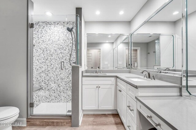 bathroom with wood-type flooring, vanity, toilet, and an enclosed shower