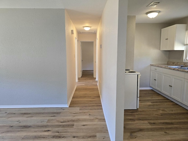 corridor featuring sink and light hardwood / wood-style flooring